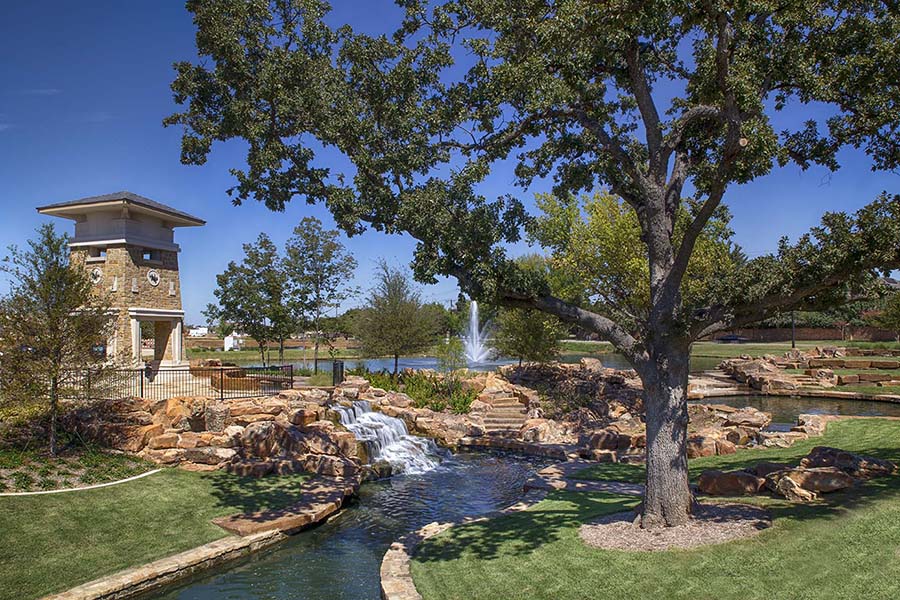 park with brick gazebo, artificial waterfalls and streams, fountains, and a large tree in the foreground